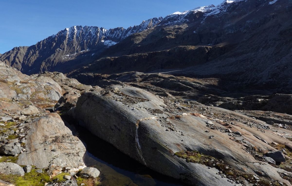Felsen mit Kies und Moos im Vordergrund, Berge im Hintergrund